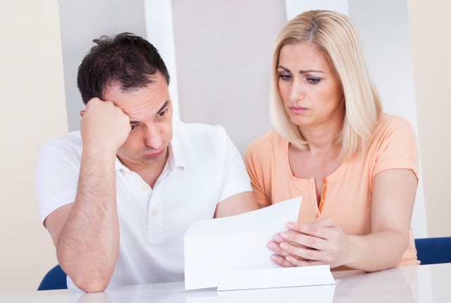 a man and woman sitting at a table looking at papers