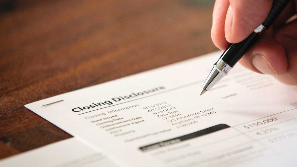 a person holding a pen and writing on a piece of paper