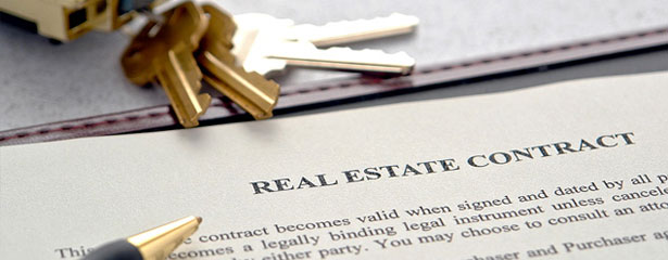 a real estate contract with keys on top of it