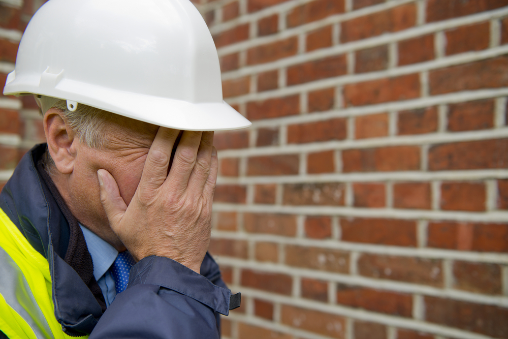 a man wearing a hard hat and holding his hands to his face