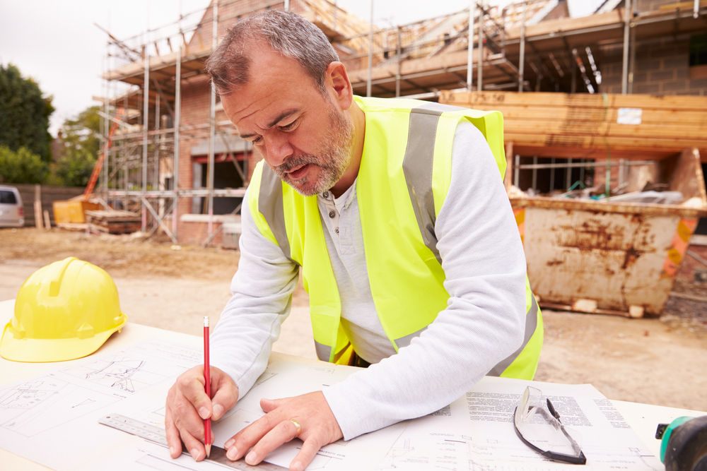 a man in a safety vest writing on a construction plan