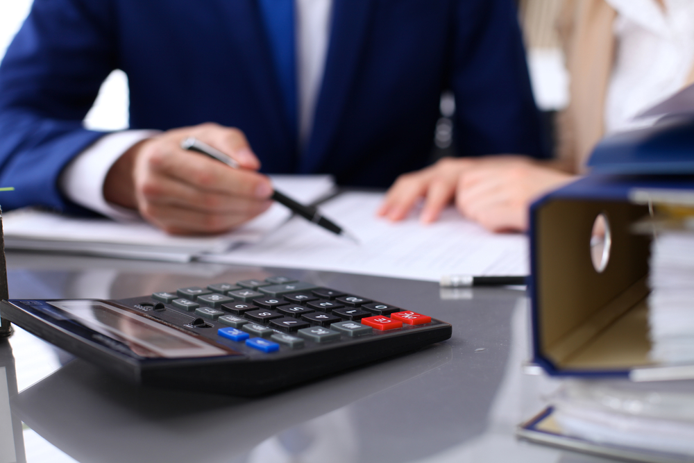 a man and woman sitting at a table with a calculator