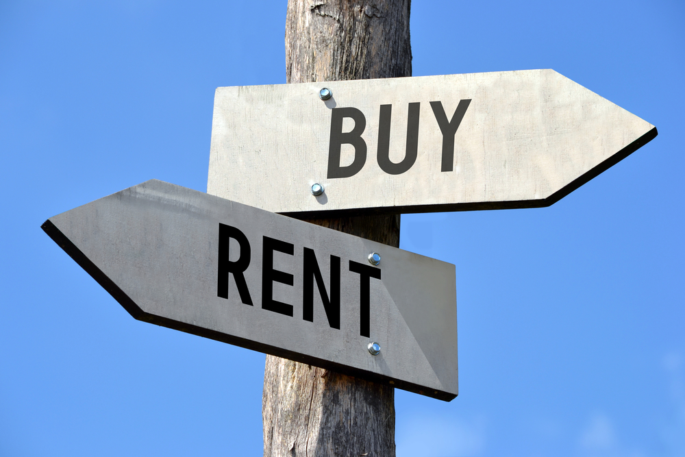 two street signs pointing in opposite directions to buy and rent