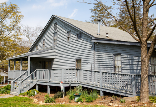 a blue house with a porch next to a tree