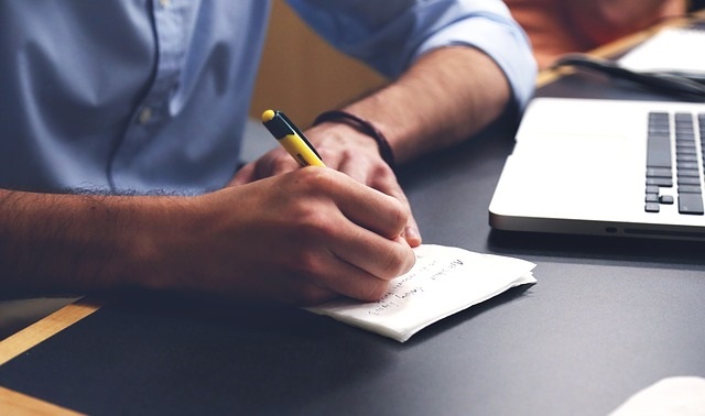 a man sitting at a desk writing on a piece of paper