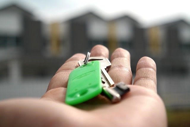 a hand holding keys in front of a row of houses