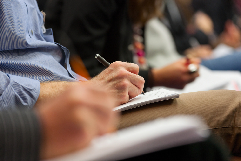 a person writing on a piece of paper with a pen