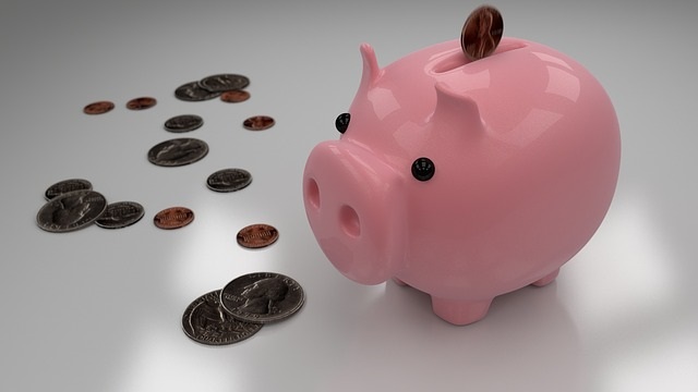 a pink piggy bank sitting on top of a pile of coins