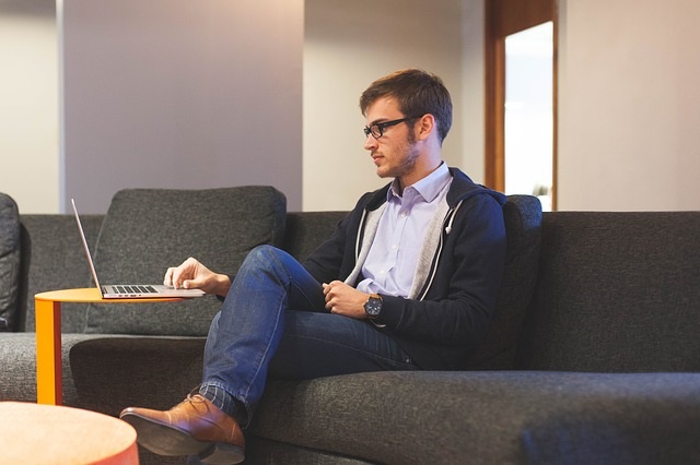 a man sitting on a couch using a laptop computer