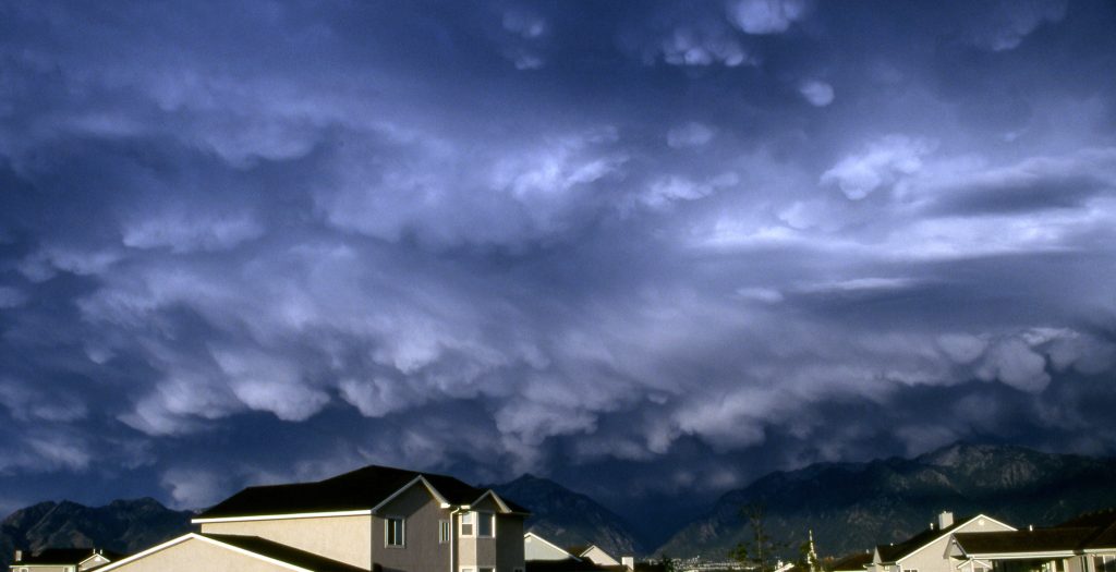 the sky is filled with dark clouds over houses