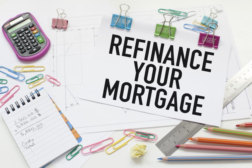 a sign that says refinance your mortgage surrounded by office supplies