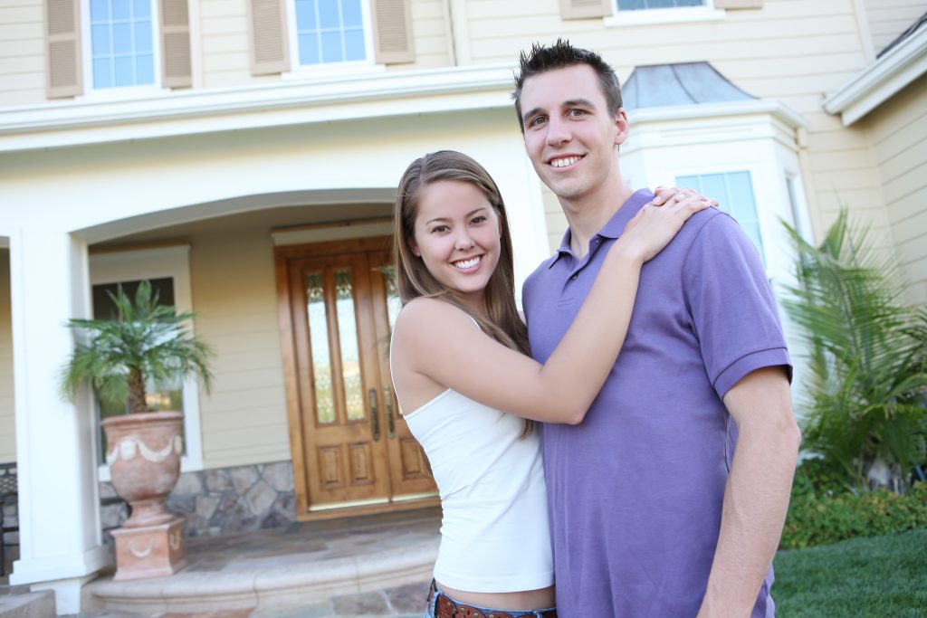 a man and woman standing in front of a house