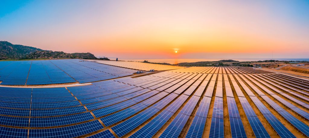 the sun is setting over rows of solar panels