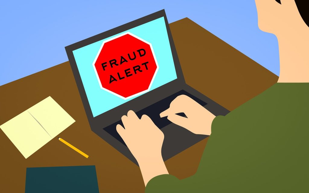 a person using a laptop computer with the word fraud alert on it
