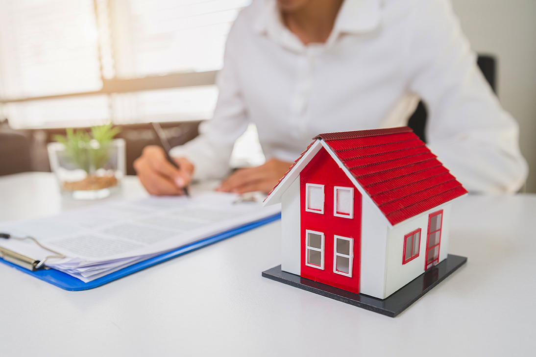 a woman sitting at a desk with a red house model