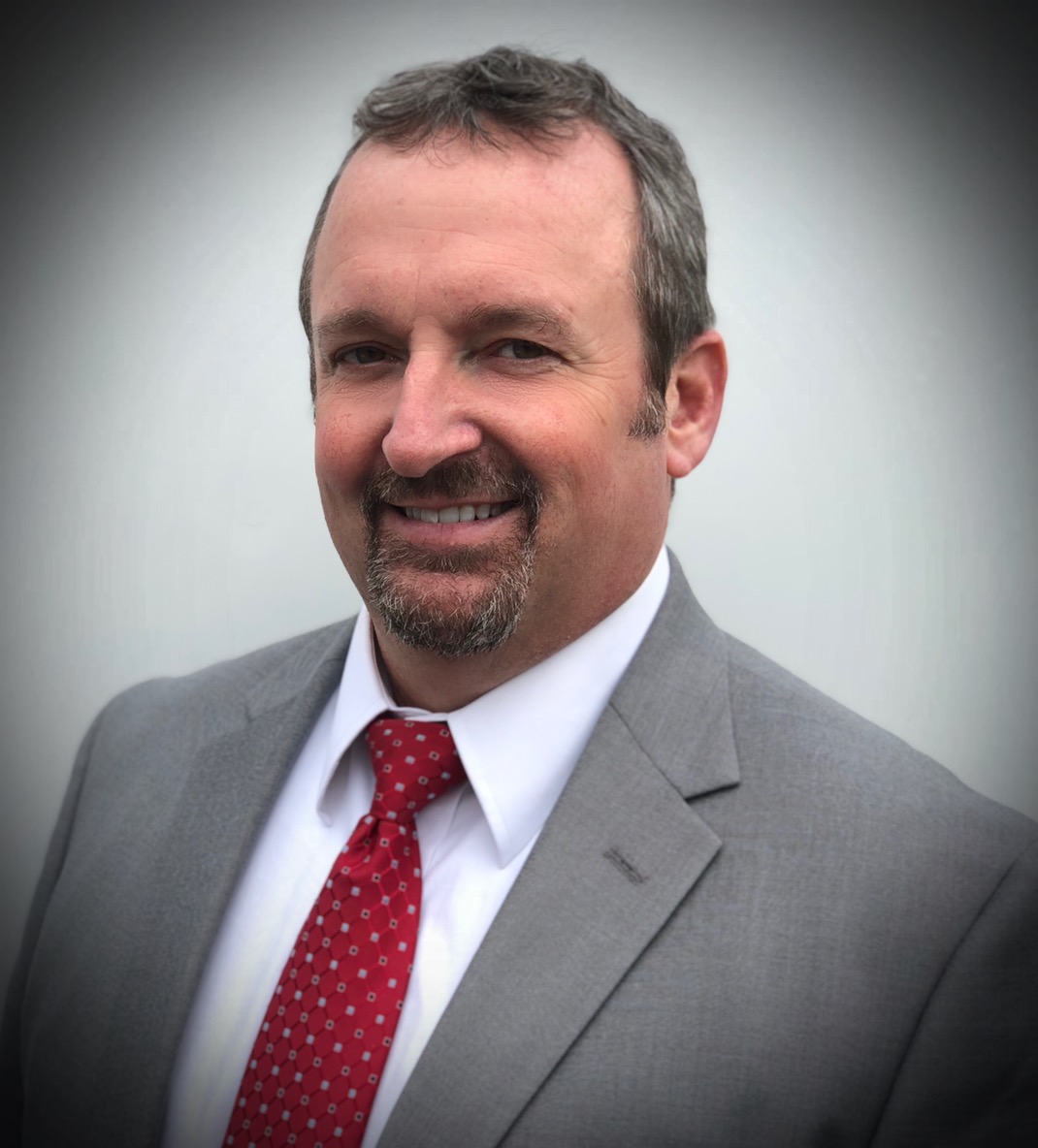 a man in a suit and tie smiling at the camera