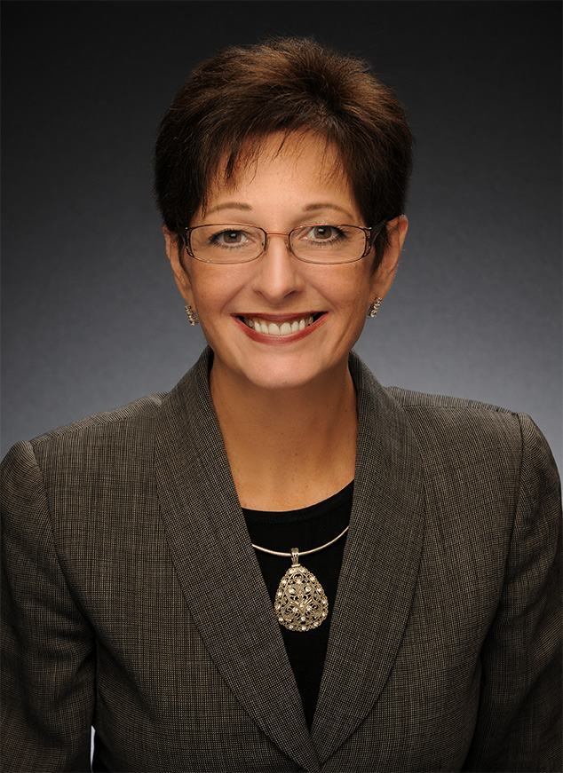 a woman wearing glasses and a jacket smiling
