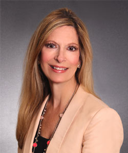 a woman with long blonde hair wearing a tan blazer