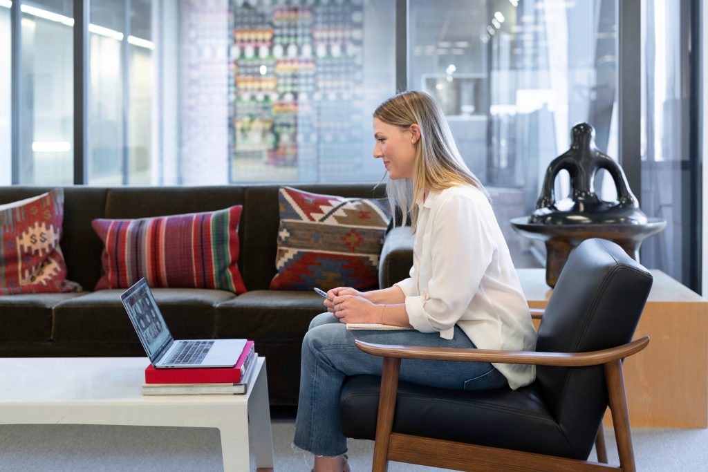 a woman sitting on a chair in front of a laptop computer