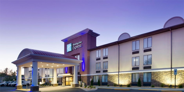 the front of a hotel at night with lights on