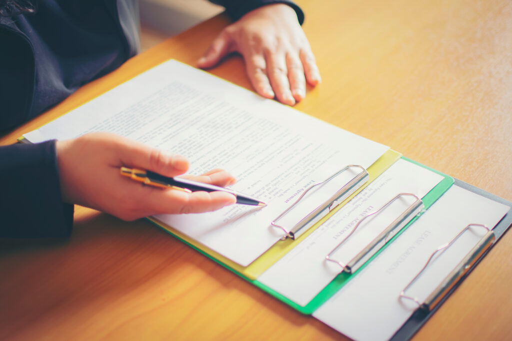 Picture of a man signing paperwork, new home in background