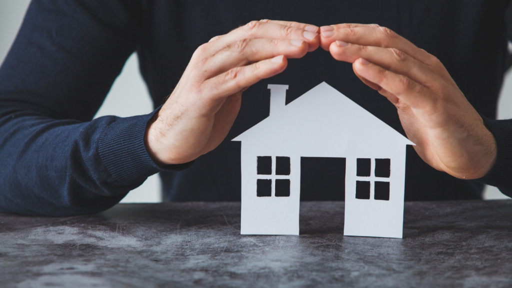 two hands hovering over a paper house