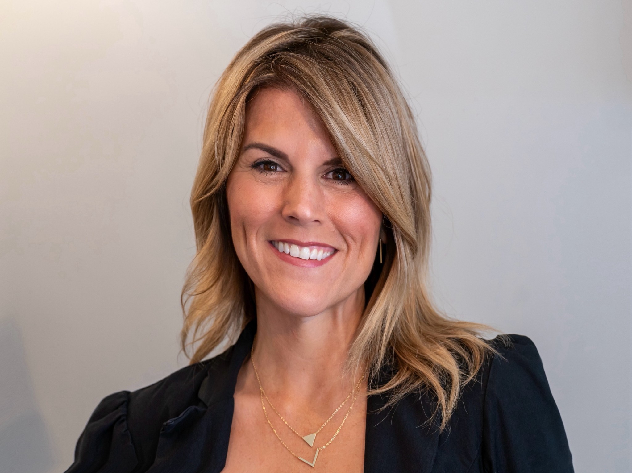a woman in a black blazer smiling at the camera